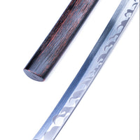 A close-up studio shot of a Japanese-style sword with a patterned silver blade and a dark brown wooden scabbard on a plain white background.